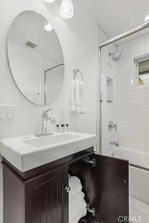 full bath featuring visible vents, vanity, and shower / tub combination