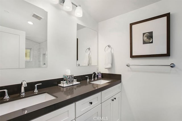 bathroom featuring a sink, visible vents, a shower, and double vanity