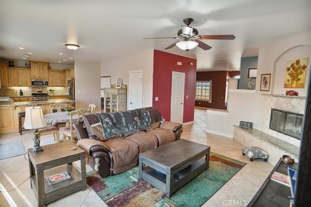 living area featuring baseboards, light tile patterned floors, recessed lighting, a fireplace, and a ceiling fan