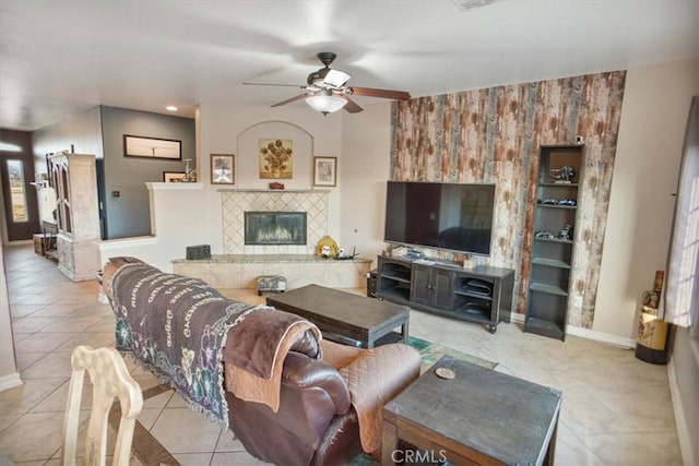 living area featuring tile patterned floors, baseboards, a fireplace, and a ceiling fan