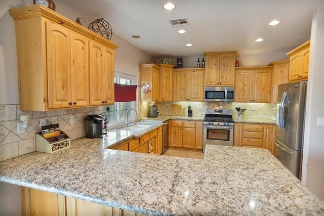 kitchen featuring backsplash, appliances with stainless steel finishes, light stone countertops, and a sink