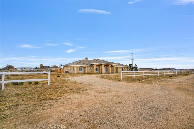 view of front of house with a rural view and fence