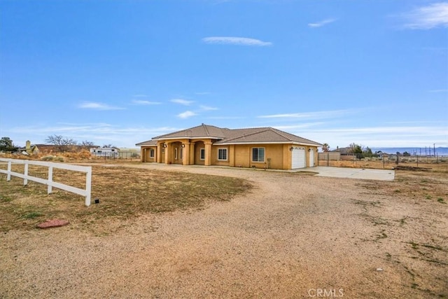 view of front of home with stucco siding, driveway, an attached garage, and fence