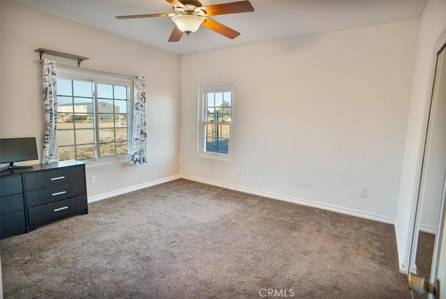 unfurnished bedroom with baseboards, dark carpet, and ceiling fan