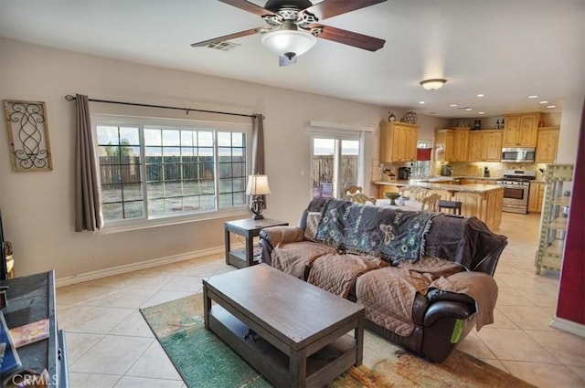 living area featuring light tile patterned floors, a ceiling fan, visible vents, and baseboards