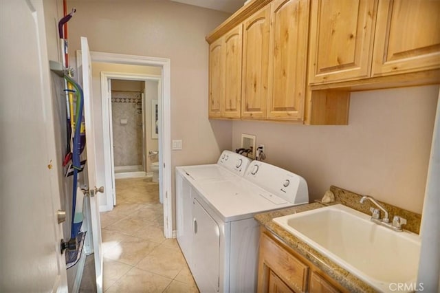 clothes washing area featuring washing machine and clothes dryer, cabinet space, light tile patterned flooring, and a sink