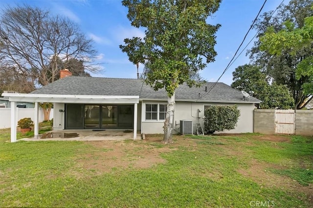 rear view of property with fence, central AC, stucco siding, a yard, and a carport