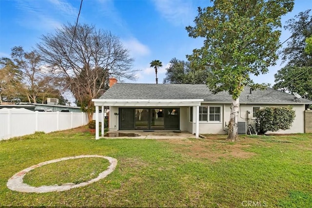 rear view of house with a patio area, a yard, fence, and stucco siding