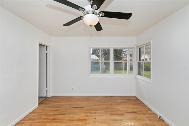 empty room featuring light wood-type flooring, baseboards, a healthy amount of sunlight, and ceiling fan