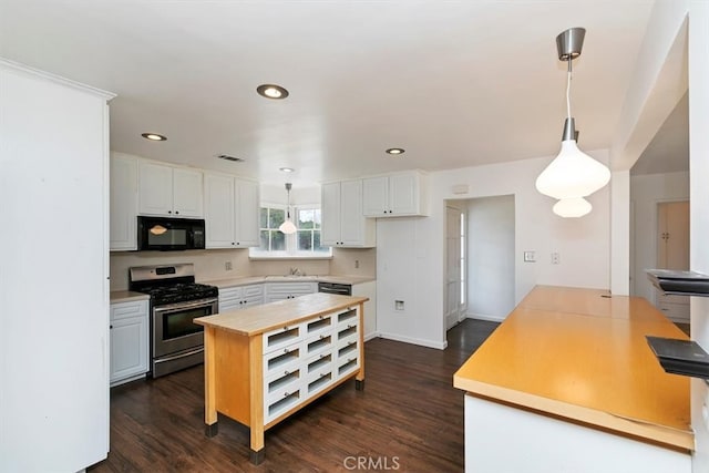 kitchen with visible vents, dark wood-type flooring, white cabinets, black microwave, and stainless steel gas stove