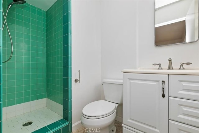 bathroom with toilet, vanity, and a tile shower