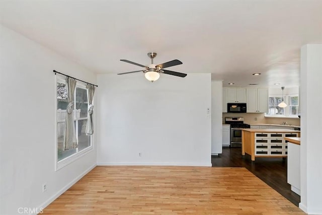 unfurnished living room with ceiling fan, baseboards, and wood finished floors