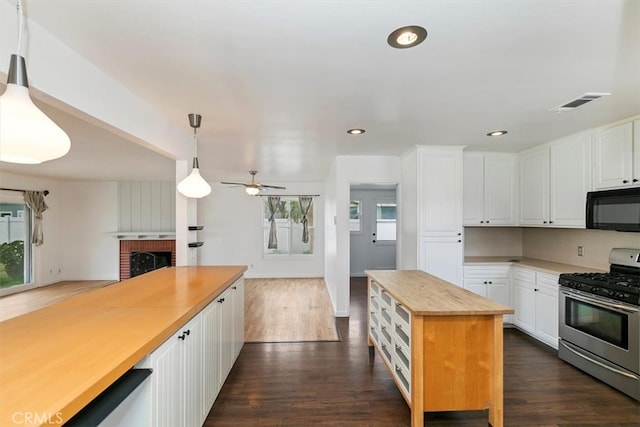 kitchen featuring gas stove, dark wood-style flooring, black microwave, and wood counters