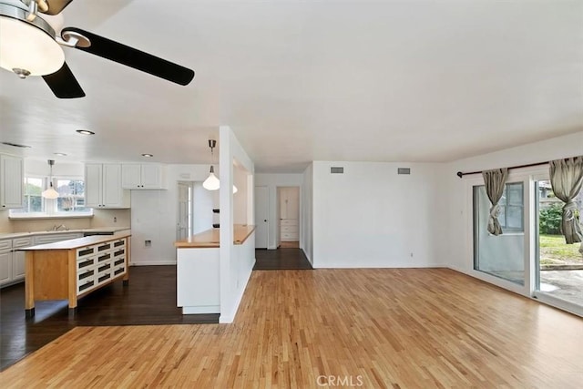 kitchen featuring open floor plan, white cabinets, light countertops, and wood finished floors