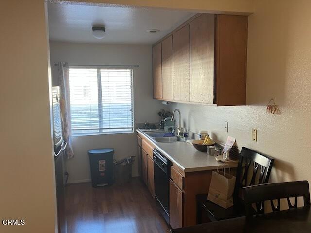 kitchen featuring dishwasher, light countertops, dark wood-style floors, and a sink