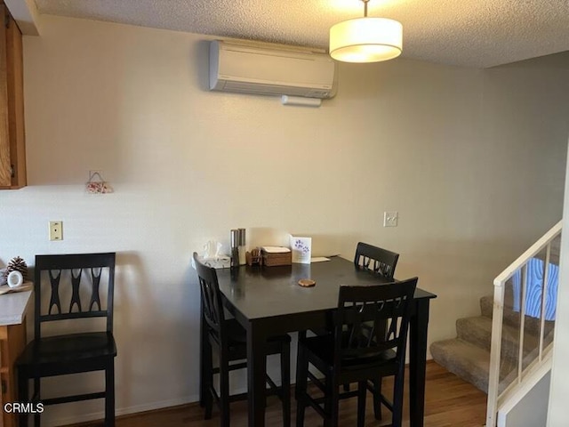 dining space with a wall mounted air conditioner, stairway, a textured ceiling, and wood finished floors