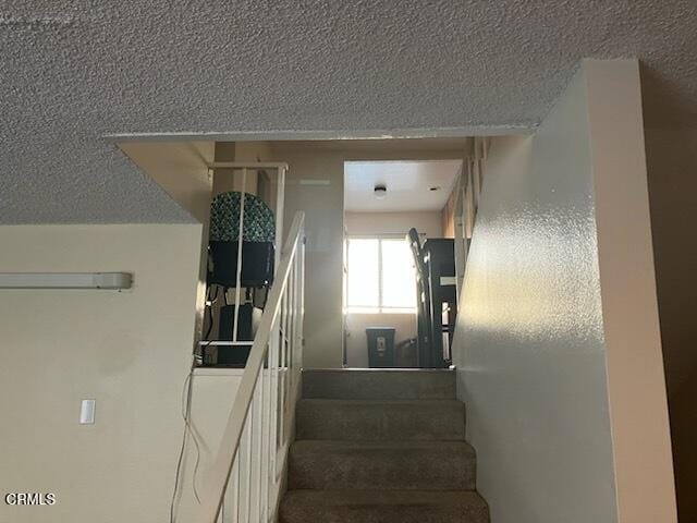 staircase featuring a textured ceiling