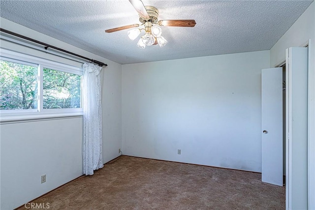 carpeted spare room with a textured ceiling and a ceiling fan