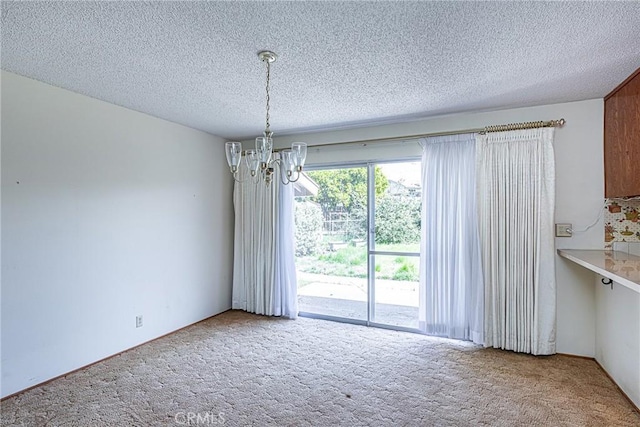 unfurnished dining area with a notable chandelier, carpet, and a textured ceiling