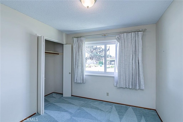 unfurnished bedroom featuring carpet flooring, baseboards, a closet, and a textured ceiling