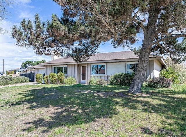 ranch-style home featuring board and batten siding, a front yard, and a garage