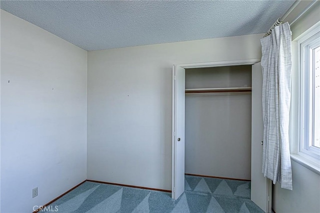 unfurnished bedroom featuring a closet, carpet flooring, a textured ceiling, and baseboards