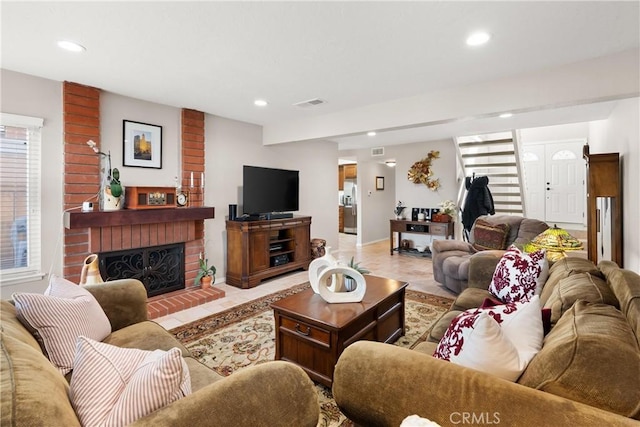 living area featuring a brick fireplace, light tile patterned floors, recessed lighting, and visible vents