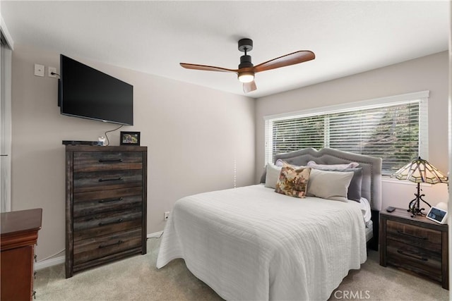 bedroom featuring baseboards, light colored carpet, and a ceiling fan