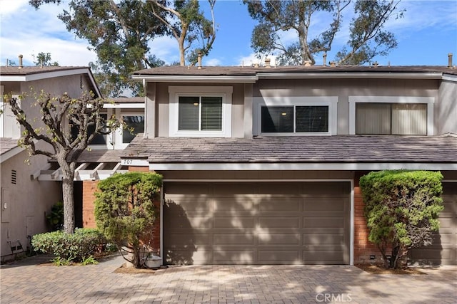 view of front of house featuring brick siding, stucco siding, driveway, and a garage