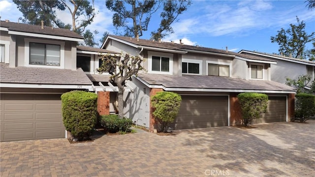 view of property with decorative driveway, a garage, and stucco siding