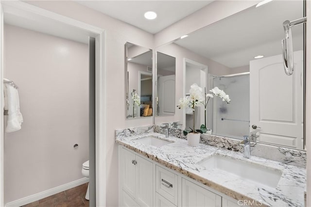 full bathroom with toilet, baseboards, a stall shower, and a sink