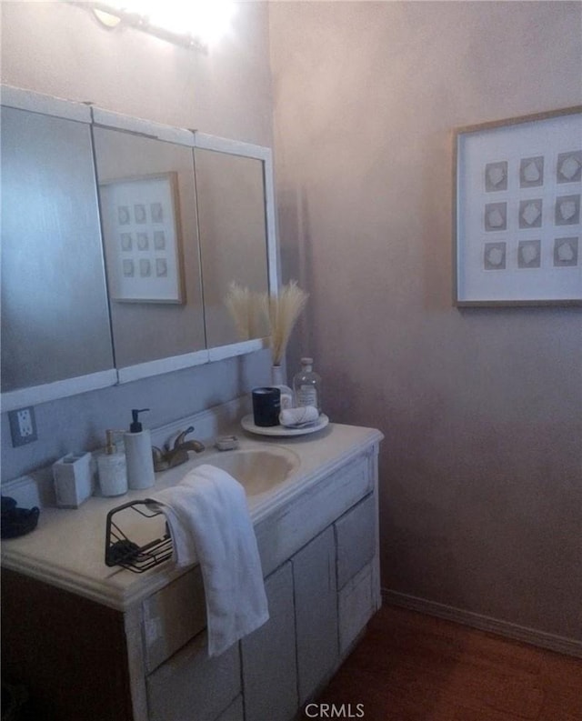 bathroom featuring baseboards, wood finished floors, and vanity