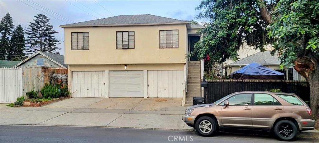 view of front facade with fence, an attached garage, stucco siding, a shingled roof, and concrete driveway