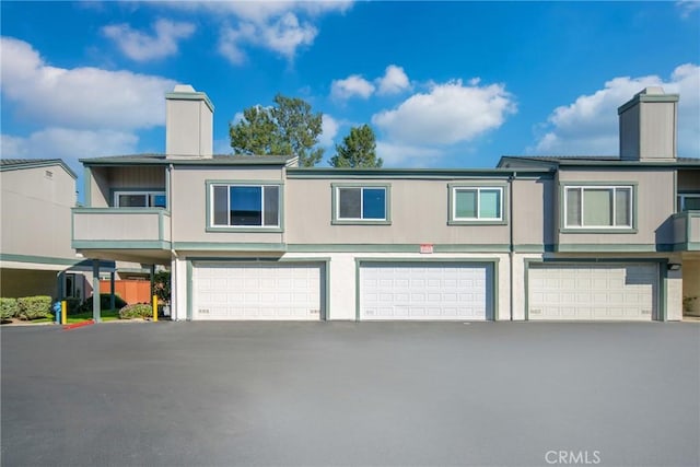 view of front of house featuring a garage, driveway, and a chimney