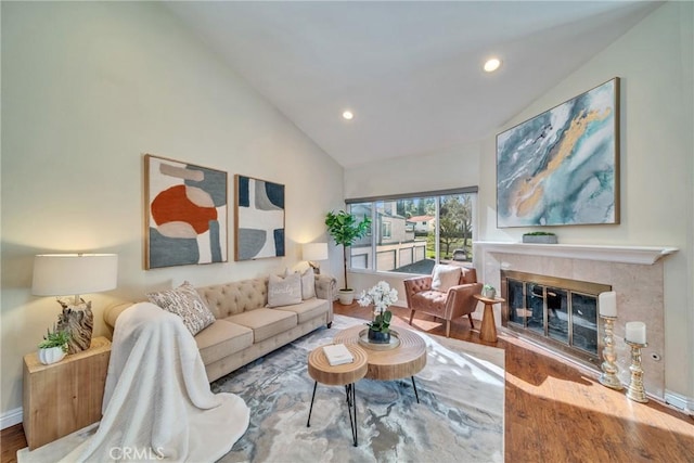 living area featuring baseboards, recessed lighting, a tile fireplace, wood finished floors, and high vaulted ceiling