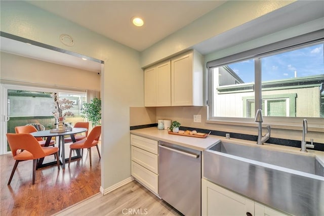 kitchen featuring light wood-type flooring, light countertops, recessed lighting, stainless steel dishwasher, and a sink