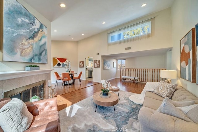 living room featuring visible vents, wood finished floors, recessed lighting, baseboards, and a towering ceiling