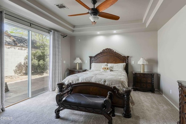 bedroom with carpet floors, a raised ceiling, and access to outside