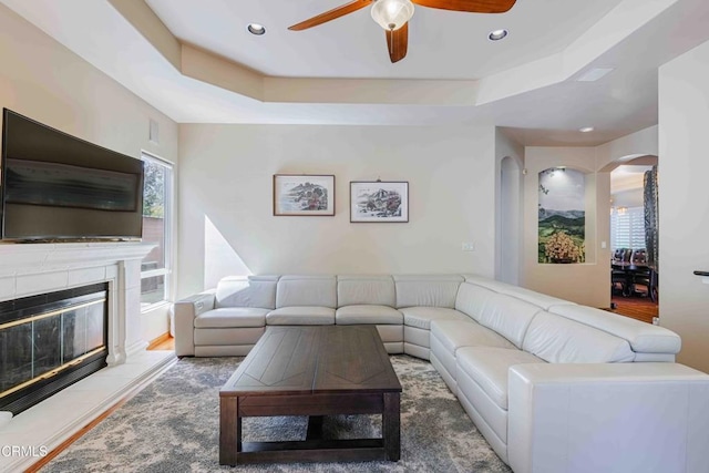 living room featuring a raised ceiling, recessed lighting, a ceiling fan, and arched walkways