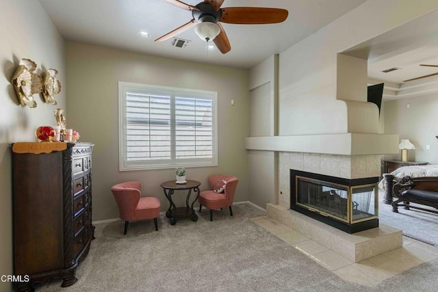 sitting room with visible vents, a tile fireplace, a ceiling fan, and carpet floors