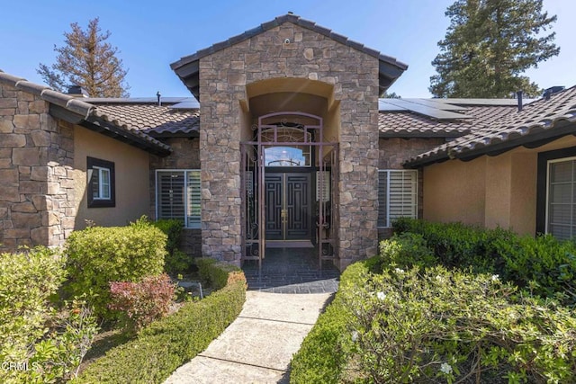 doorway to property with stucco siding, stone siding, and a tile roof