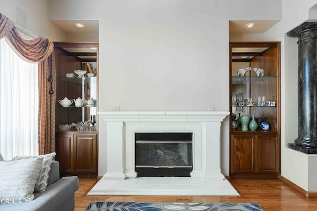 living room with decorative columns, wood finished floors, and a fireplace