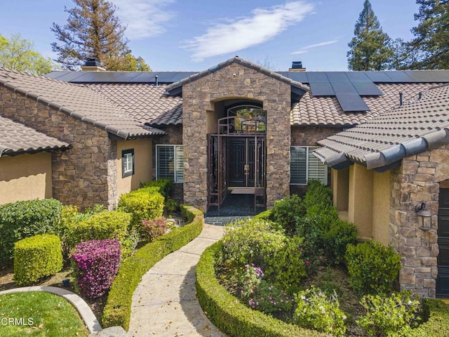 property entrance with stucco siding, stone siding, and a chimney