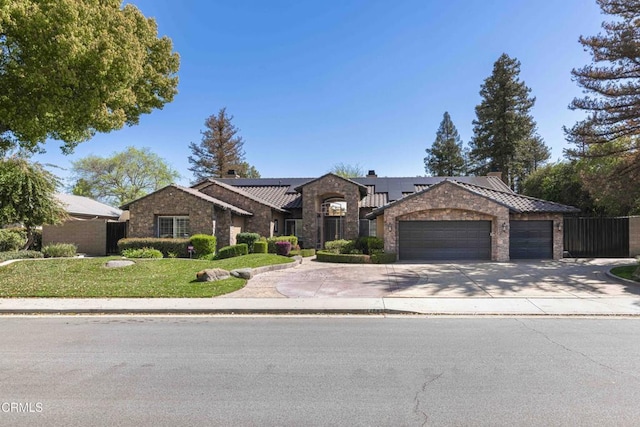 view of front facade featuring stone siding, roof mounted solar panels, fence, concrete driveway, and an attached garage