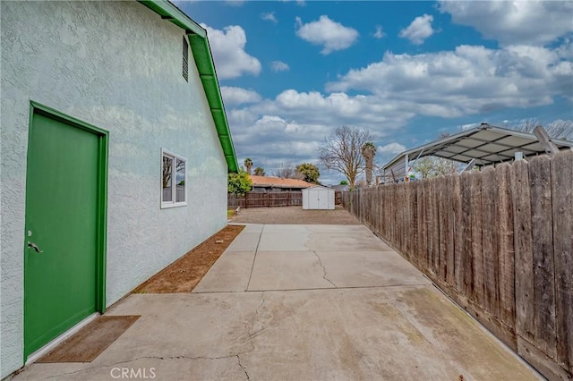 view of patio / terrace with an outdoor structure, a fenced backyard, and a shed