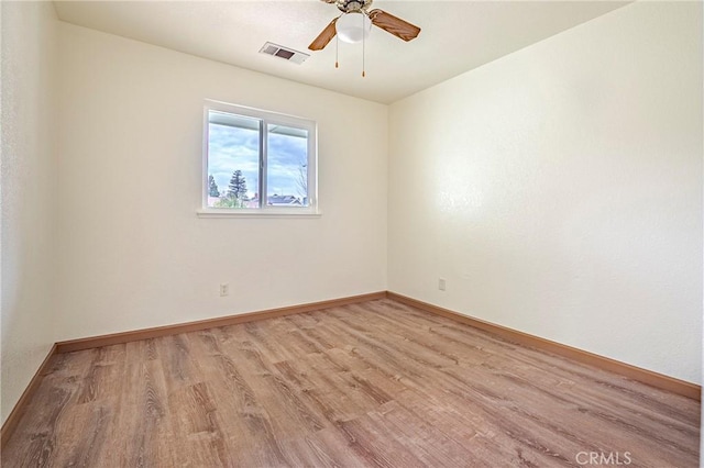 unfurnished room with a ceiling fan, visible vents, light wood finished floors, and baseboards