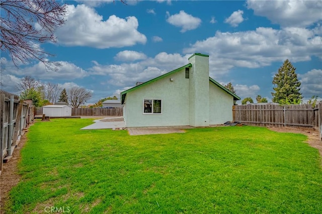 back of house with a fenced backyard, a yard, a patio area, an outdoor structure, and a storage unit