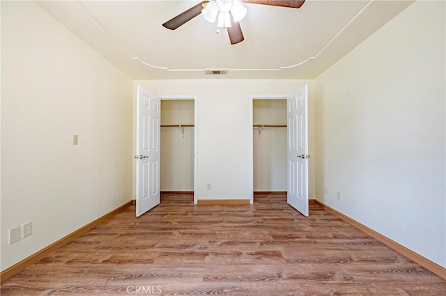 unfurnished bedroom with light wood finished floors, visible vents, baseboards, and multiple closets