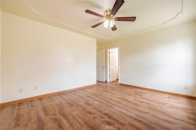 empty room with light wood-style flooring, a ceiling fan, and baseboards