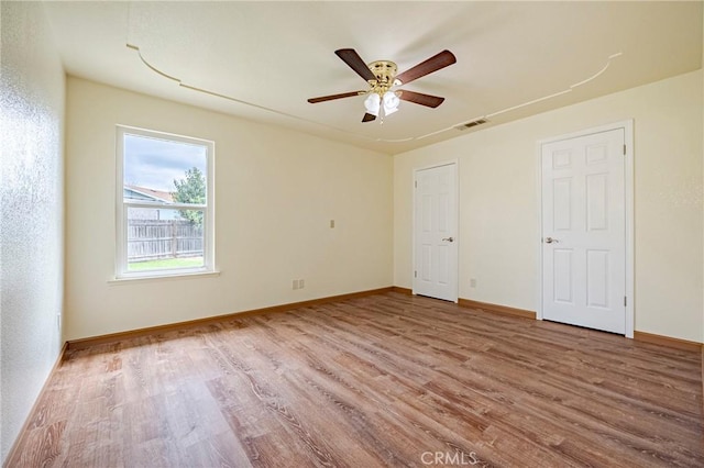 empty room featuring visible vents, baseboards, ceiling fan, and wood finished floors